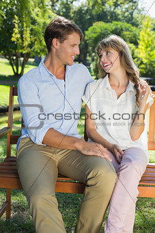 Cute couple sitting on park bench together chatting