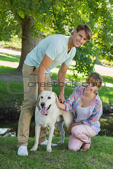 Happy couple with their labrador in the park smiling at camera