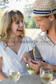 Man placing engagement ring on smiling fiancees finger