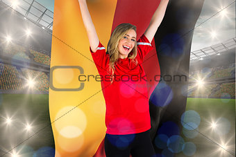 Composite image of cheering football fan in red holding german flag