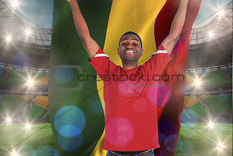 Composite image of excited handsome football fan cheering holding ghana flag