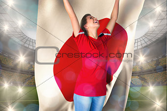 Composite image of cheering football fan in red holding japan flag
