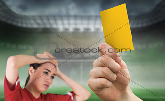 Composite image of hand holding up yellow card to fan