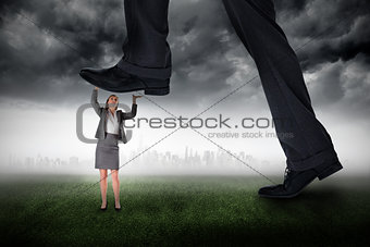 Composite image of businessman stepping on tiny businesswoman