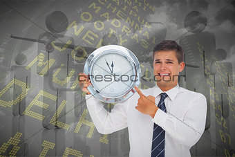 Composite image of anxious businessman holding and showing a clock