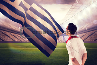 Composite image of handsome football fan looking ahead