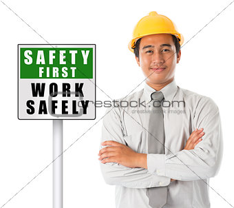 Asian male wearing yellow hardhat with safety first sign board.