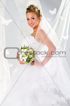 Beautiful bride with bouquet of flowers over summer background
