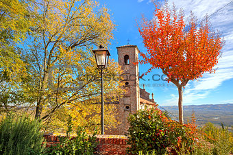 Old belfry among autumnal trees in Piedmont, Italy.