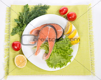 Raw salmon steak red fish on a plate decorated with vegetables 