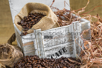 scattered roasted coffee beans in front of old wooden box with a