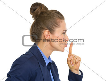 Profile portrait of business woman showing shh gesture