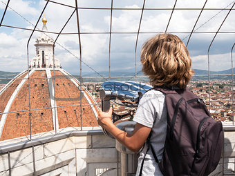 Boy looking through a sightseeing binoculars the Dome of Basilic
