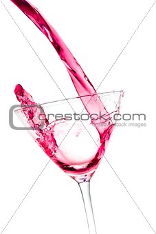 pouring a glass with red cocktail tilted and splashing