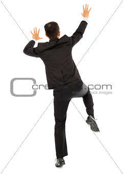 full length of young business man climbing a wall