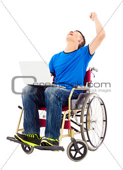  young man sitting on a wheelchair and  excited to raise arm