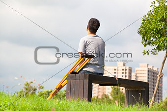 Injured Man with Crutches sitting on a bench