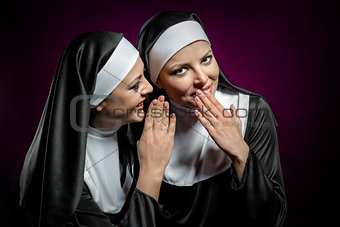 Young attractive nun whispering a secret to another nun 