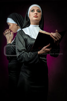 Two attractive young nuns with rosary and bible praying