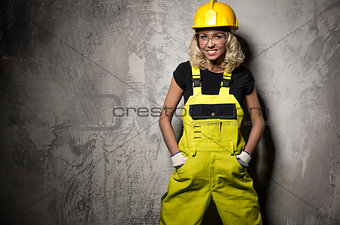 Attractive builder woman posing against grunge wall
