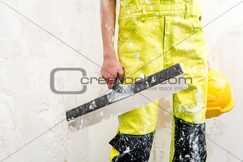 Construction worker with putty knife over obsolete background