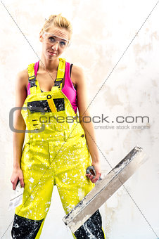Tired female construction worker with putty knife working indoor