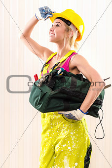 Female construction worker with tool bag indoors 