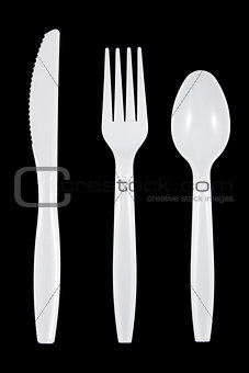 White plastic knife, fork and spoon on black background.