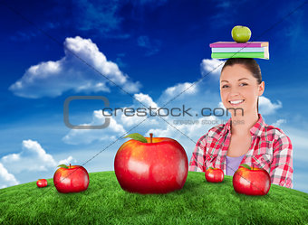 Composite image of pretty student holding an apple and books on her head