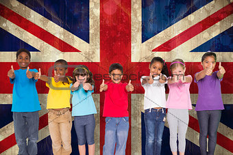 Composite image of elementary pupils smiling showing thumbs up