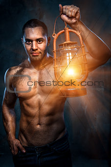 Muscular build man holding oil lamp