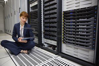 Technician sitting on floor beside server tower using tablet pc
