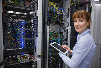 Smiling technician using tablet pc while analysing server