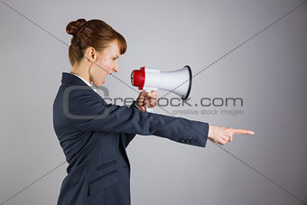 Angry businesswoman shouting through megaphone and pointing