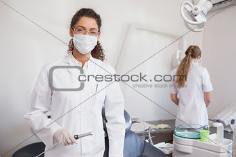 Dentist smiling at camera holding suction tube