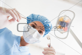 Dentist in surgical mask and cap holding dental tools