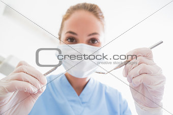 Dentist in surgical mask holding tools over patient