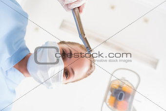 Dentist in surgical mask holding dental drill over patient