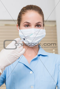 Dental assistant holding injection looking at it