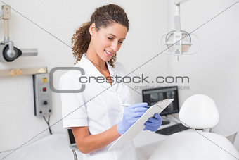 Dental assistant writing in clipboard