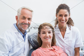 Dentist his assistant and patient all smiling at camera