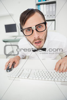 Nerdy shocked businessman working on computer