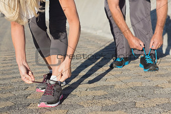 Couple tying their laces of running shoes