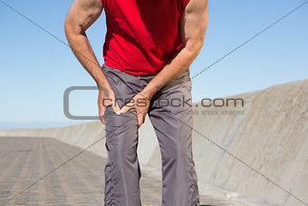 Active senior man touching his injured thigh
