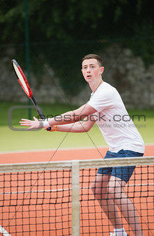 Young tennis player hitting ball