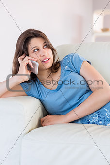 Pretty brunette making a call on the couch