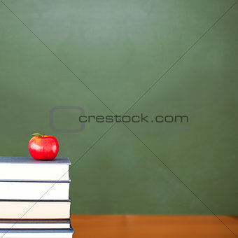 Red apple on pile of books in classroom