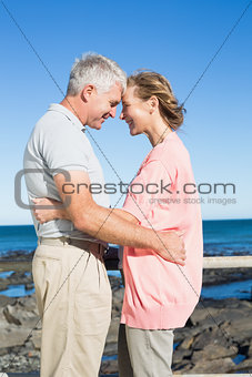 Happy casual couple smiling at each other by the coast