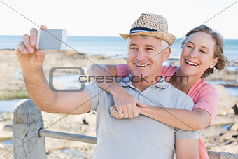 Happy casual couple taking a selfie by the coast