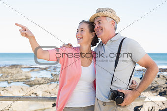 Happy casual couple looking at something by the coast